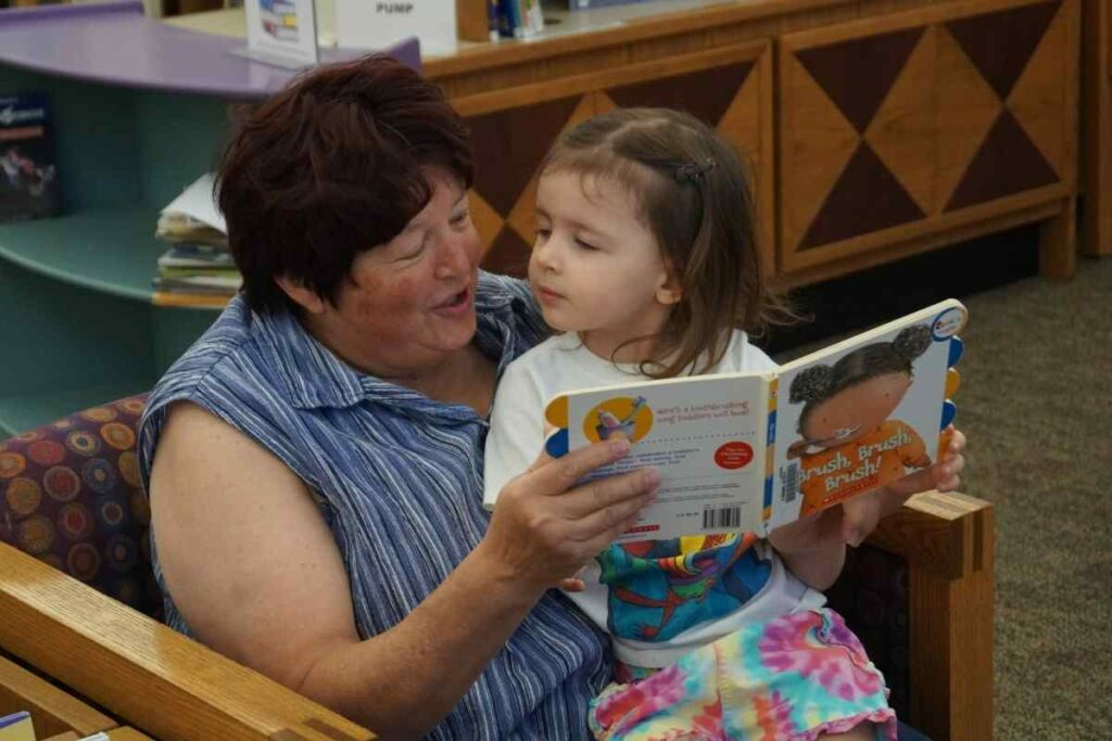 woman reading picture book to preschooler